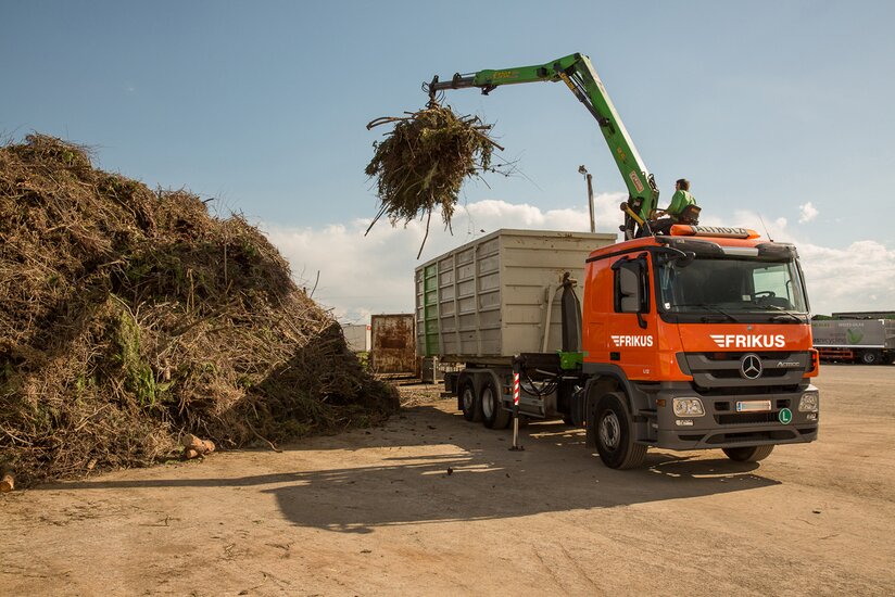 Mann entsorgt Holz mit Kran auf Lkw.