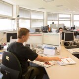 Mann sitzt im Büro vor Bildschirm.