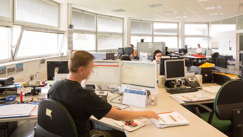 Mann sitzt im Büro vor Bildschirm.