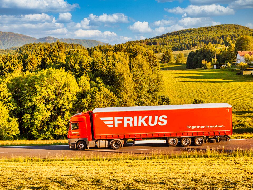 Lkw auf Landstraße grüne Landschaft im Hintergrund.