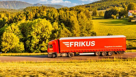 Lkw auf Landstraße grüne Landschaft im Hintergrund.
